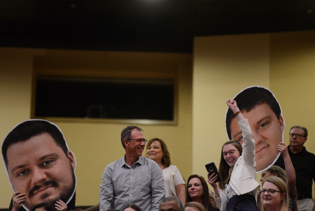 Family members wave giant prints of the graduates' heads during commencement